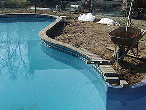 Towaco, NJ - Bull nose paver brick coping being installed on existing pool - Vreeland Landscapes