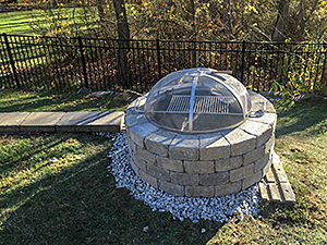Rockaway, NJ - Custom built fire pit with grill installed at end of retaining wall.  Note the cap block has not been installed yet. - Vreeland Brothers Landscaping