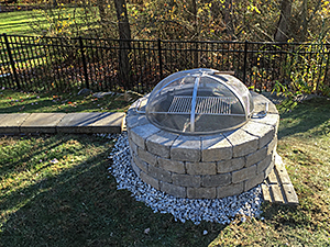 Rockaway, NJ - Custom built fire pit with grill installed at end of retaining wall.  Note the cap block has not been installed yet. - Vreeland Landscapes