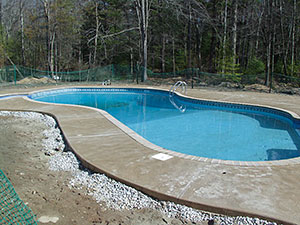 West Milford, NJ - Swirl finish concrete pool patio & bull nose coping installed around new pool - Vreeland Landscapes